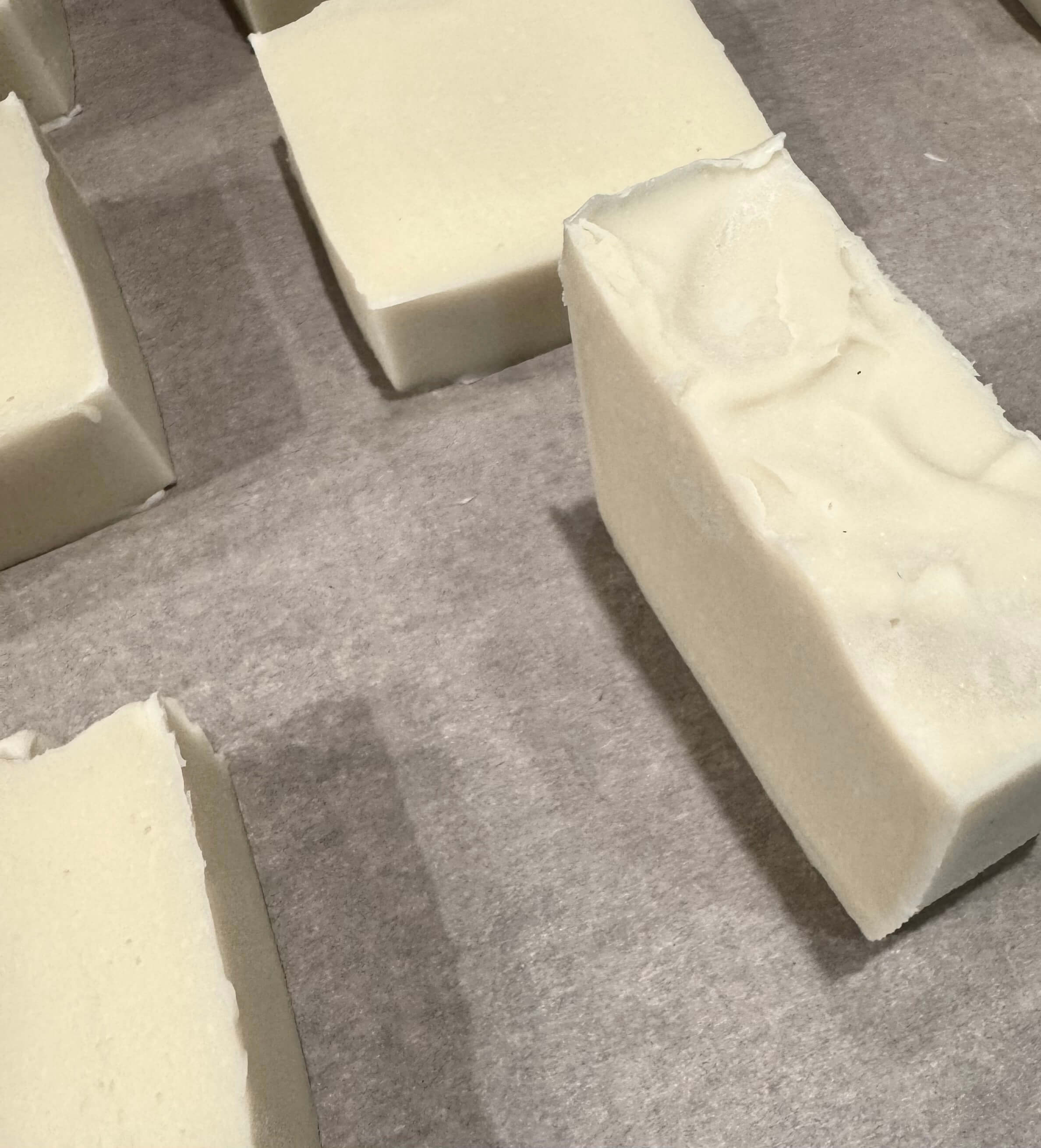 Hand-cut bars of milk soap curing on parchment paper